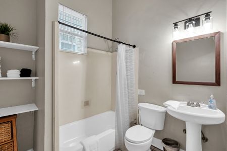 Clean bathroom w/ a tub/shower combo, white tile & plenty of space.