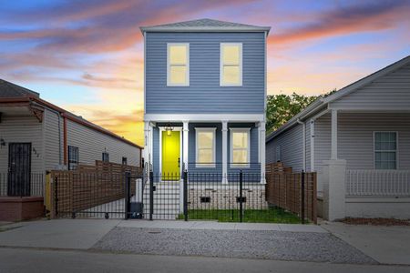 Charming blue exterior w/ a bold yellow door glowing at golden hour.