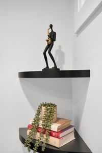 Sleek black shelf w/ a golden sculptural figure adds an artful, modern touch.