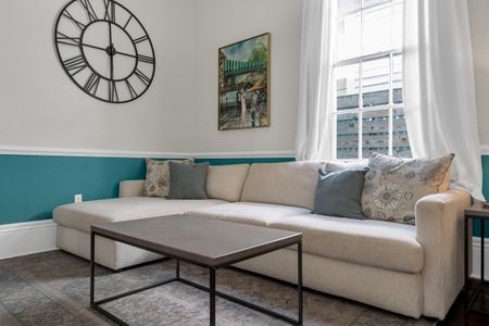 Sun-drenched living room w/ neutral tones & a fireplace — made for lounging.