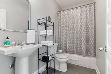 Clean bathroom w/ a tub/shower combo, toilet & handy storage shelving.