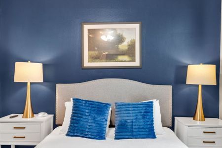 Plush bed w/ tufted headboard & bold blue pillows for a restful night's sleep.