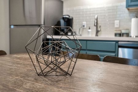 Geometric light fixture & teal kitchen details adding a modern artistic touch.
