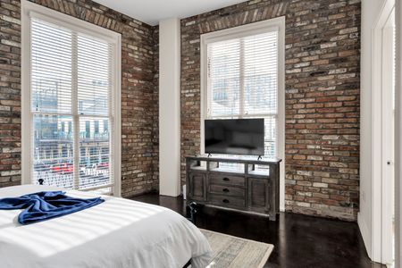 Cozy corner bedroom w/ charming exposed brick & warm-toned decor.