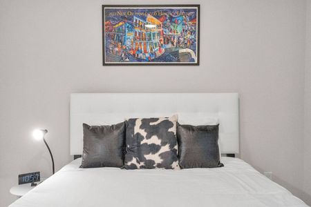 Sunlit bedroom w/ bold artwork & cozy bedding to wake up feeling refreshed.