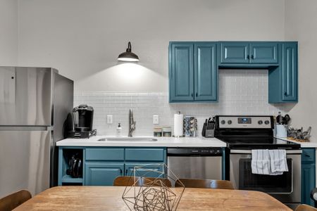 Stylish kitchen w/ bold teal cabinets, open shelving & modern appliances.