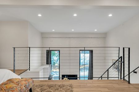 The loft overlooks the bright living space below, with plenty of natural light and modern railings for a sleek, spacious vibe.