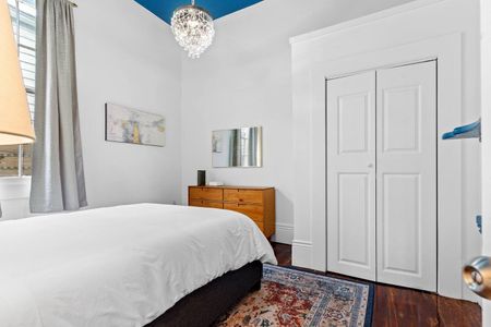Clean, simple bedroom w/ white walls & natural light — a calm retreat.
