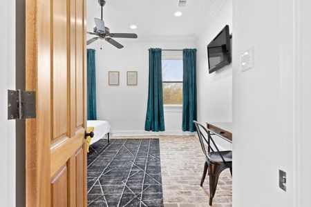 Bedroom 1 entrance w/ charming brick floors & teal curtains that set a bold, cozy tone.