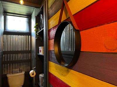 Stylish entryway w/ a round mirror & bold orange accent — a great first impression.