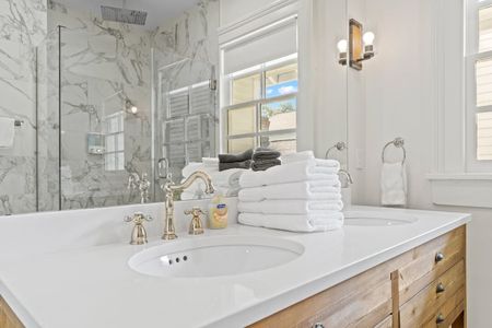 Bright bathroom vanity w/ sink, gold fixtures & neatly folded fresh towels.