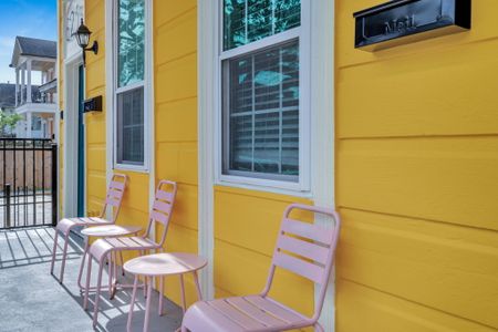 Sunny porch w/ seating & a cheerful yellow façade — soak up that New Orleans charm.