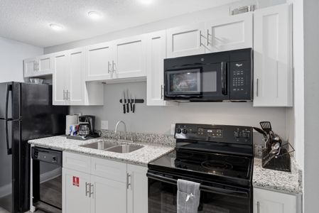 Modern kitchen w/ black appliances & clean white finishes.