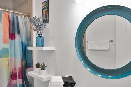 Teal round mirror & blue floral arrangement bring a playful, curated energy.