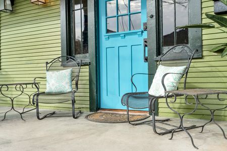 Charming private patio w/ seating framed by a bold teal entry door.