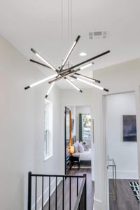 Dramatic sputnik chandelier casting a warm, sculptural glow in the hallway.