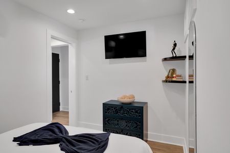 Bedroom 1 w/ a wall-mounted TV & minimalist shelf for a clean, clutter-free feel.