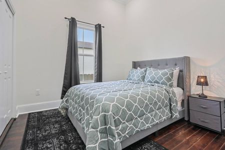 Restful bedroom w/ a patterned comforter & soft natural light.