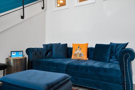 Sink into a plush blue velvet sofa w/ a cheerful orange pillow accent.