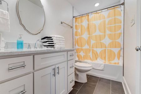 Cheerful bathroom w/ a bold patterned curtain & classic round mirror.