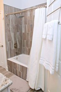 Spa-like bathroom w/ earthy tile & neatly folded fresh towels.