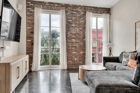 Sun-drenched living room w/ exposed brick & floor-to-ceiling windows.