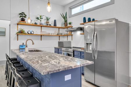 Kitchen w/ marble-look counters, open shelving, & blue cabinetry — sleek & functional.