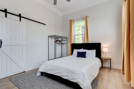 Airy queen bedroom w/ golden curtains & natural light — a calm, restful escape.