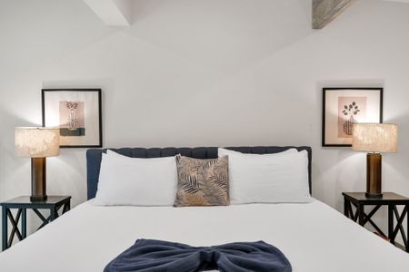 Comfortable bed w/ crisp linens in a simply styled, restful room.