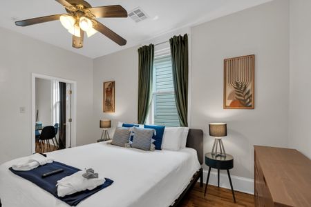 Airy bedroom w/ a neatly made bed & warm natural light.