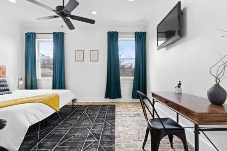 Bedroom 1 w/ charming brick floors & teal curtains for a cozy, character-filled feel.