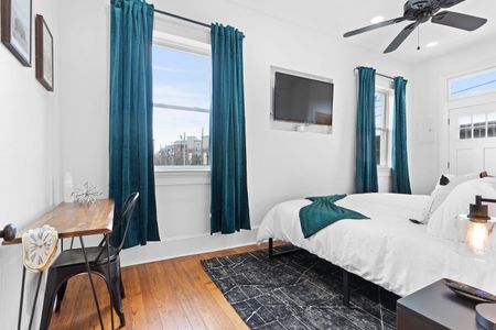 Bright bedroom 2 w/ teal curtains, a cozy bed & direct access to the balcony.