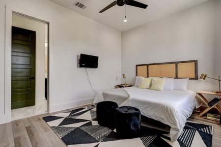 Bedroom w/ a woven headboard, pocket door & clean, airy finishes.