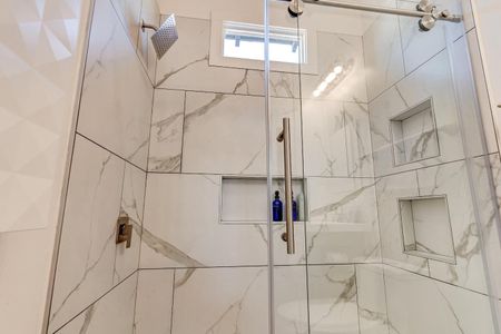 Stunning marble-look tiled shower w/ a built-in niche — a luxurious rinse awaits.