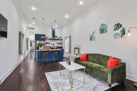 Bright living room w/ a green sofa, white coffee table & a peek into the kitchen.