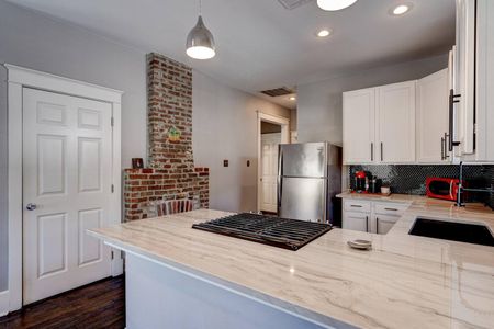 Bright kitchen w/ exposed brick accent & stainless steel fridge.