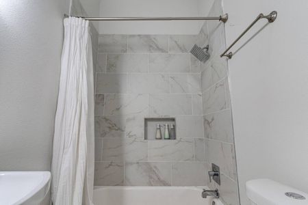 Tiled shower w/ sleek marble-look walls — a refreshing way to start or end your day.