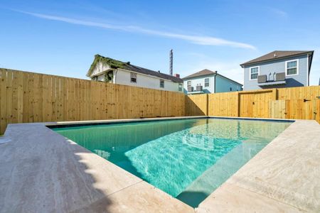 Sparkling pool w/ a gentle water feature tucked behind a tall privacy fence.