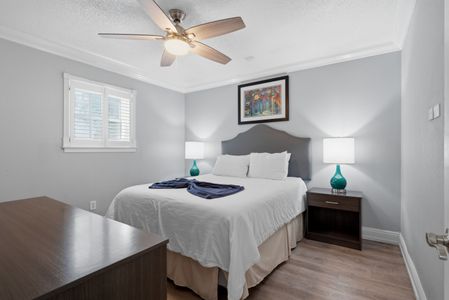 Bright bedroom w/ warm lamp glow & a neatly made bed.