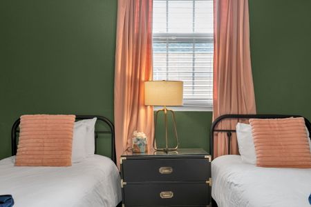 Warm-lit bedroom w/ a bed, sage walls & flowing peach curtains for a calm night in.
