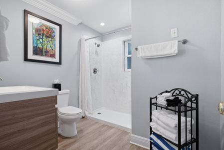 Bright bathroom w/ walk-in shower & neatly stocked essentials.