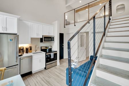 Sleek kitchen & staircase flow seamlessly into the bright, open main space.