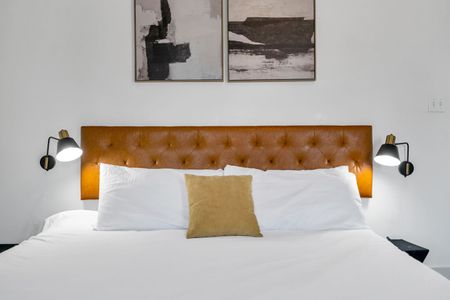 Close-up of a tufted orange headboard w/ layered pillows for a luxe, boutique feel.