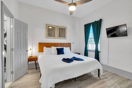Cozy bedroom w/ teal curtains, layered blue bedding, & a warm, restful atmosphere.