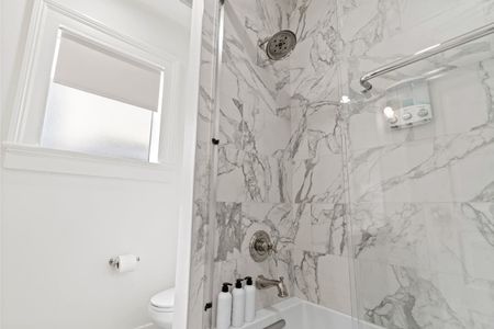 Elegant bathroom w/ marble-look walls & a sleek shower.