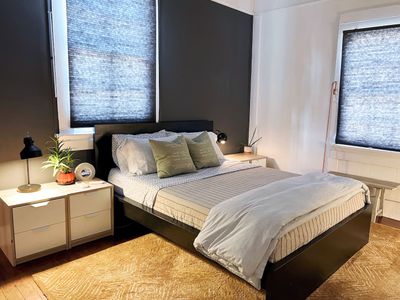 Cozy bedroom w/ a made bed, soft linens & warm, moody tones.
