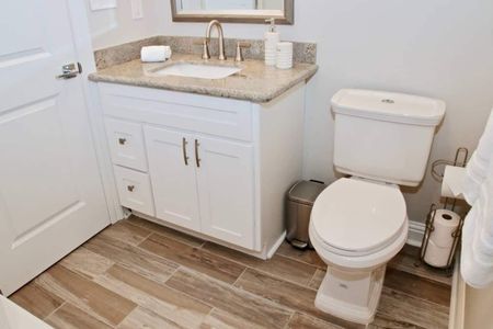 Spotless second hall bathroom w/ a white vanity, sink & toilet.