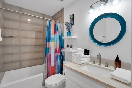 Bathroom w/ a sink, colorful shower curtain & tiled walls.