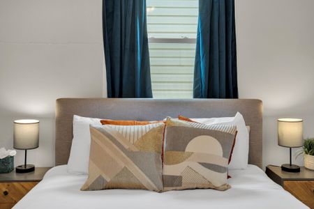Bed w/ warm, layered pillows in earthy tones for a relaxed, welcoming vibe.