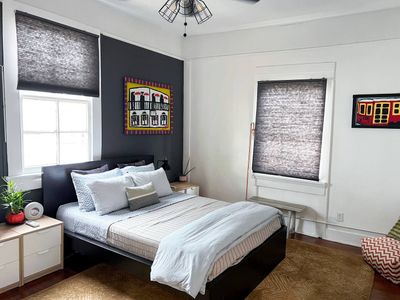 Restful bedroom w/ neatly made bed & natural light streaming through the windows.